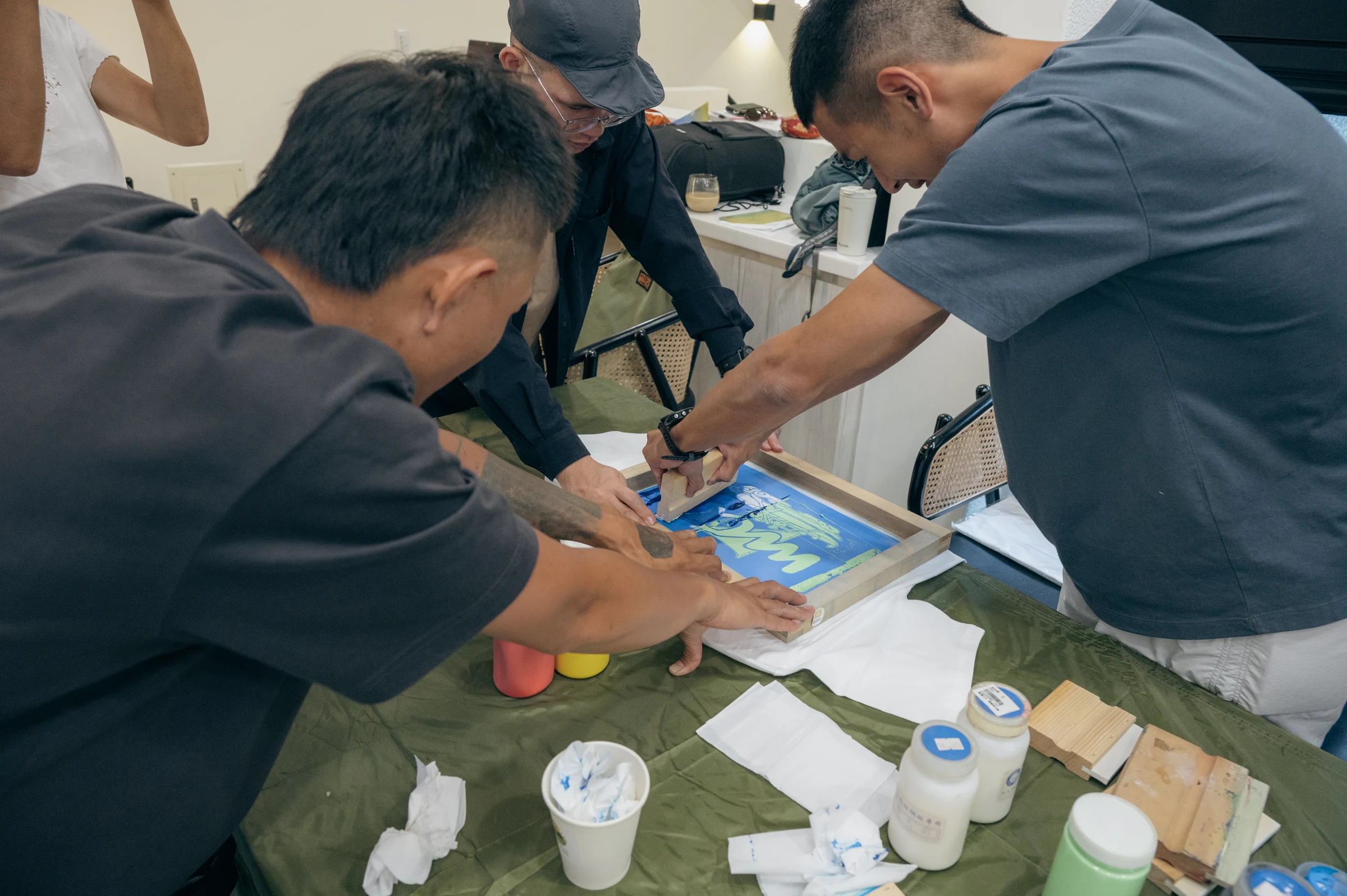 三位參與者合作固定網版並刮印航海圖樣